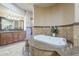Bathroom featuring a whirlpool tub with tile surround, double sink vanity, and neutral decor at 18131 W Palo Verde Ct, Litchfield Park, AZ 85340