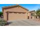 Tan two-story home featuring a wide garage, desert landscaping, and a well-maintained front yard at 20934 N Sweet Dreams Dr, Maricopa, AZ 85138