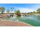 Scenic pond featuring a rock waterfall, lush landscaping, and American flags at 20934 N Sweet Dreams Dr, Maricopa, AZ 85138