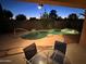 Covered patio and a sparkling pool at dusk, perfect for relaxing and enjoying the evening at 20934 N Sweet Dreams Dr, Maricopa, AZ 85138