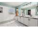 Bright bathroom with dual sinks, white cabinets, quartz countertops, and a tiled shower with glass door at 31301 N Sunflower Way, San Tan Valley, AZ 85143