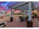 Charming brick patio with a pergola, dining set, and views of the expansive backyard at dusk at 31301 N Sunflower Way, San Tan Valley, AZ 85143