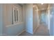 Hallway with neutral paint and carpet features niche with a framed decorative piece at 37262 W Oliveto Ave, Maricopa, AZ 85138