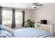 Bedroom with a comfortable blue striped bed, lots of natural light from large windows, and a modern TV stand at 3802 E Shaw Butte Dr, Phoenix, AZ 85028