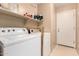 Functional laundry room equipped with a washing machine, dryer, and storage shelving at 45 S 238Th Dr, Buckeye, AZ 85396