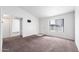 A vacant living room with white walls, tan carpet, and a door and large window for ample sunlight at 461 W Holmes -- # 342, Mesa, AZ 85210
