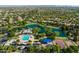 High-angle aerial view of a vibrant community featuring lush landscaping, a pool, and a scenic pond at 4630 E Carriage Ct, Gilbert, AZ 85297