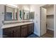 Double sink vanity with decorative mirrors, granite counters, and walk-in closet access at 4637 E Fernwood Ct, Cave Creek, AZ 85331