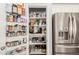Well-organized walk-in pantry with shelving and a variety of food items, adjacent to a stainless steel refrigerator at 4791 S White Pl, Chandler, AZ 85249