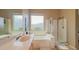 Bright bathroom featuring a large window, a luxurious tub, a glass-enclosed shower, and tiled flooring at 522 S 122Nd Ln, Avondale, AZ 85323