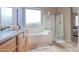 Bright bathroom featuring dual sinks, a large tub, and a glass-enclosed shower, perfect for relaxation and convenience at 522 S 122Nd Ln, Avondale, AZ 85323