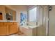 Bright bathroom with a white tub, glass shower, a large window, and ample natural light for a refreshing experience at 522 S 122Nd Ln, Avondale, AZ 85323