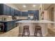 Open kitchen with a large island, stainless appliances, barstool seating and stylish blue cabinetry at 522 S 122Nd Ln, Avondale, AZ 85323