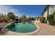 Backyard pool area with lush desert landscaping and adjacent brick patio area at 522 S 122Nd Ln, Avondale, AZ 85323