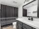 A modern bathroom features a sleek black vanity, white countertop, and a stylish patterned shower curtain at 807 E Harvard Ave, Gilbert, AZ 85234