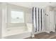 The bright bathroom includes a tub, shower with a patterned curtain, and a window at 807 E Harvard Ave, Gilbert, AZ 85234