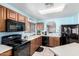 Traditional kitchen with wooden cabinets, black appliances, and a breakfast bar opening to another room at 10510 W Louise Dr, Peoria, AZ 85383