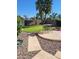 A cozy backyard featuring a dining table, brick fireplace and manicured lawn, surrounded by stone landscaping at 1213 N Raven --, Mesa, AZ 85207