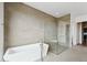 Modern bathroom featuring soaking tub, shower with glass door, and floor to ceiling tile at 13116 E Desert Holly Dr, Scottsdale, AZ 85255