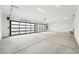 Spacious three car garage featuring two glass panel garage doors, white walls and ceiling and concrete floor at 13116 E Desert Holly Dr, Scottsdale, AZ 85255