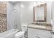 Bright bathroom featuring a tub and shower combo with stylish stone and tile, plus granite countertop and a wood framed mirror at 14240 S Overfield Rd, Arizona City, AZ 85123