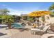 Inviting backyard featuring a private pool, charming rock waterfall, desert landscaping, and lounge seating under a yellow umbrella at 14442 N Prickly Pear Ct, Fountain Hills, AZ 85268