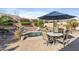 Spacious backyard featuring a pool with rock features, desert landscaping, outdoor dining area, and patio seating under a blue umbrella at 14442 N Prickly Pear Ct, Fountain Hills, AZ 85268