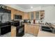 Corner view of kitchen featuring black appliances, light wood cabinets, and sink near an open spice rack at 1717 E Union Hills Dr # 1065, Phoenix, AZ 85024