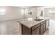 A kitchen island features a granite countertop, stainless steel sink, and stylish dark cabinets at 17843 W Encinas Ln, Goodyear, AZ 85338