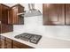Close-up of gas cooktop, stainless hood, white backsplash, and dark wood cabinetry in modern kitchen at 18166 E Colt Dr, Queen Creek, AZ 85142