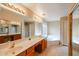 Bathroom featuring double sinks, a large mirror, and a soaking tub at 19507 N 90Th Ln, Peoria, AZ 85382