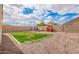 Large backyard with green grass, gravel, high brick wall, play house, shed, chairs, and beautiful skies at 28916 N Selenite Ln, San Tan Valley, AZ 85143