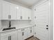 Bright laundry room with white cabinets, modern sink and hardware, and tile flooring at 35597 W Jones Ave, Tonopah, AZ 85354