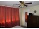 Simple bedroom with red curtains, a ceiling fan, and a dresser at 409 S Mountain View Dr, Kearny, AZ 85137