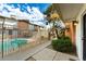 Community pool with metal safety fence, palm trees, and shared green space at 5106 N 17Th Ave # 11, Phoenix, AZ 85015