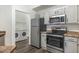 Well-lit kitchen with stainless steel appliances and white cabinets next to a laundry room with modern washer and dryer at 600 W Grove Pkwy # 2188, Tempe, AZ 85283