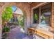 Stone archway reveals a beautifully landscaped courtyard with a fountain and mature trees at 7442 E Golden Eagle Cir, Gold Canyon, AZ 85118