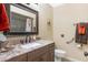 Bathroom vanity with stone countertop, decorative mirror, and accessible toilet and shower at 9501 W Hidden Valley Cir, Sun City, AZ 85351