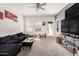 Living room features a plush black sofa, plush carpet, and ample natural light from the windows at 9509 W Illini St, Tolleson, AZ 85353