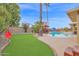 Beautiful backyard featuring a pool, putting green, lounge chairs, desert landscaping and mature palm trees at 9517 W Cedar Hill Cir # N, Sun City, AZ 85351