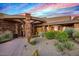 Striking front exterior showcasing natural stone accents, desert plants and an arched entry at 9962 E Groundcherry Ln, Scottsdale, AZ 85262