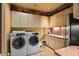 Well-organized laundry room with a side-by-side washer and dryer, and ample cabinet storage at 9962 E Groundcherry Ln, Scottsdale, AZ 85262