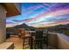 Outdoor patio with a bar-height table set that overlooks a mountain range at sunset at 9962 E Groundcherry Ln, Scottsdale, AZ 85262