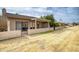 Exterior view of a home's backyard featuring a covered patio, brick pavers, and a charming wrought iron fence at 10236 E Minnesota Ave, Sun Lakes, AZ 85248