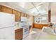 Bright kitchen featuring wood cabinetry, white appliances, and tiled flooring overlooking backyard at 10324 N 97Th Dr # B, Peoria, AZ 85345
