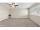 Bright living room with a ceiling fan, large windows, and neutral-toned carpet create a cozy atmosphere at 10324 N 97Th Dr # B, Peoria, AZ 85345