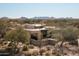 An aerial shot showcases a desert home with mountain views in the distance at 10687 E Fernwood Ln, Scottsdale, AZ 85262