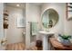 Powder room featuring a pedestal sink, round mirror and wood-look tile flooring at 10687 E Fernwood Ln, Scottsdale, AZ 85262