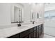 Bright bathroom featuring dual sinks, white quartz countertops, dark cabinets, and modern fixtures at 15778 W Cheryl Dr, Waddell, AZ 85355