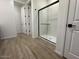 Bright bathroom showcasing a glass-enclosed shower with black trim and wood-look tile flooring at 15778 W Cheryl Dr, Waddell, AZ 85355